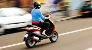 Panning shot of a young girl riding a scooter in a European city